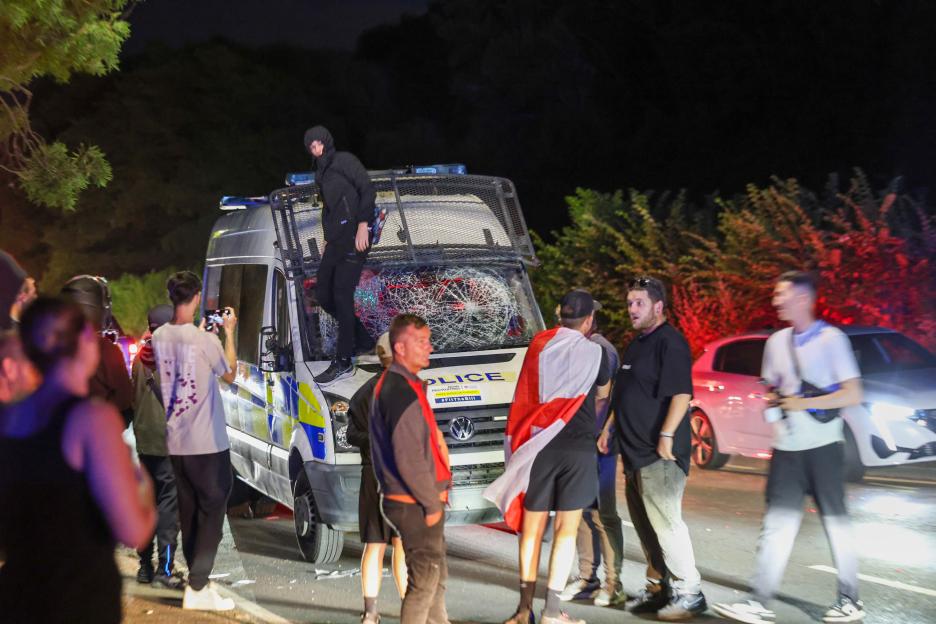 A damaged police van at a nighttime protest.
