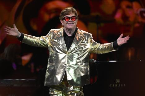 Elton John performing in a gold suit.