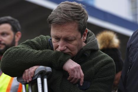A grieving man leans on crutches at a vigil.