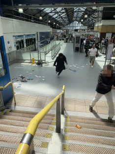 A man running through Earls Court Station as papers scatter on the ground.