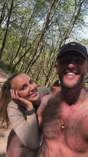 Couple posing in a wooded area.