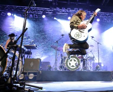 Mike Peters, The Alarm frontman, playing guitar on stage.