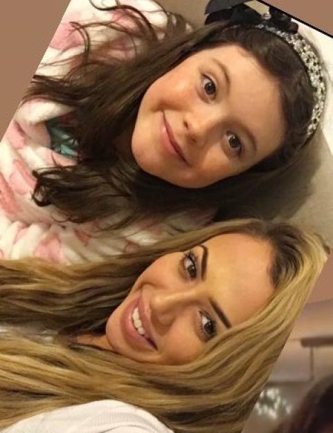 A woman with long blonde hair and a young girl with long brown hair smiling at the camera.