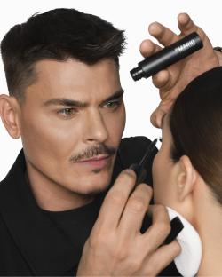 A makeup artist applying mascara to a model's eyelashes.