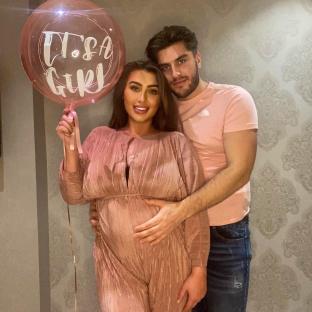 Pregnant woman and man holding a balloon that says "It's a Girl".