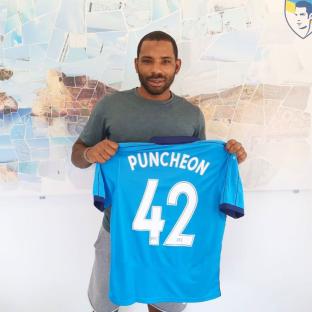 Man holding up a light blue soccer jersey with 
