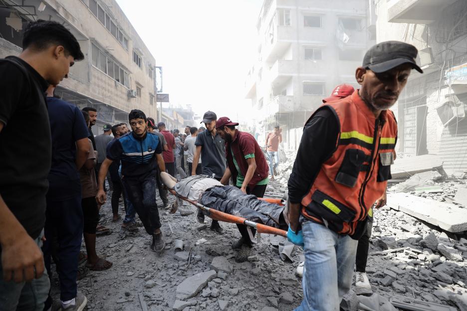 Palestinians carry an injured person on a stretcher through rubble in Gaza City after an Israeli army attack.