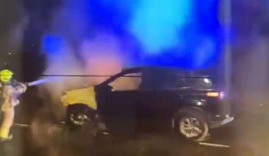 Firefighter extinguishing a burning car.