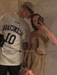 Mirror reflection of a man kissing a woman, with their toddler son standing between them.