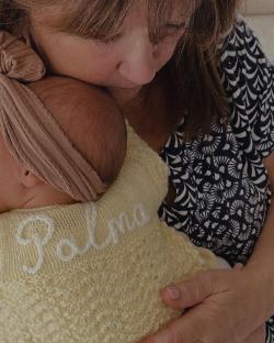 Grandmother holding baby Palma wearing a pale yellow knitted garment.