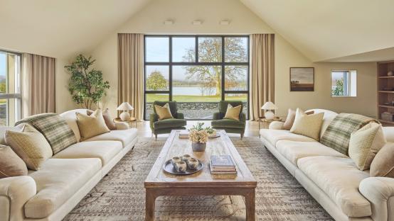 Living room with two sofas, coffee table, and large window overlooking a loch.