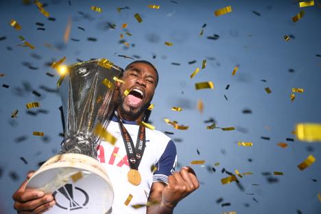 Kevin Danso of Tottenham Hotspur holding the UEFA Europa League trophy and medal, surrounded by confetti.