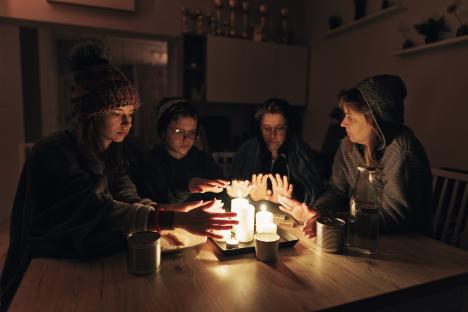 Family warming hands around lit candles during a power outage.