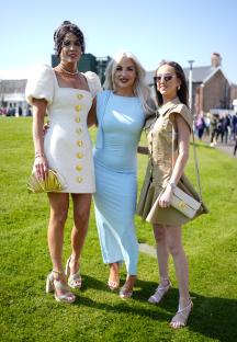 Three women in dresses at a horse race.