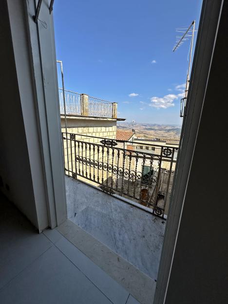 View from a doorway of a balcony overlooking a town and rolling hills.