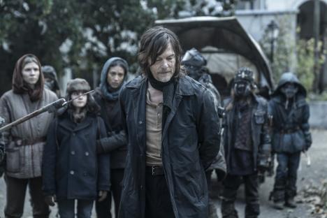 Daryl Dixon surrounded by a group of people on a road.