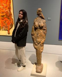 Woman standing next to a sculpture in an art gallery.