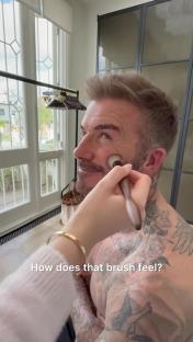 David Beckham having makeup applied by a brush.
