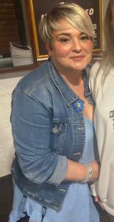 Woman in denim jacket and light blue dress.