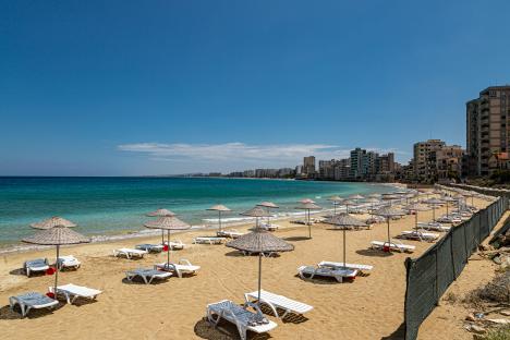 Beach with umbrellas and lounge chairs in front of abandoned hotels in Varosha, Northern Cyprus.