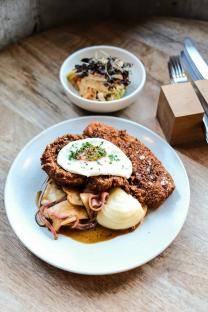 Fried cutlet with fried egg, mashed potatoes, and sauteed mushrooms and onions.