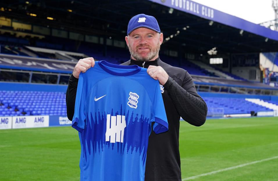Wayne Rooney holding a Birmingham City football shirt.