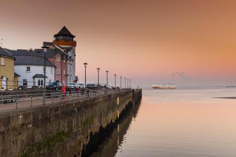 Portishead marina at sunset with a cargo ship in the distance.