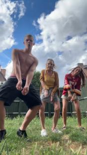 Three people dancing in a garden.