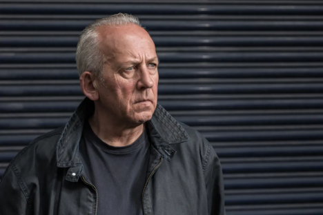 Portrait of a serious-looking older man in a dark jacket.