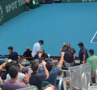 Security escorting someone from a tennis match.