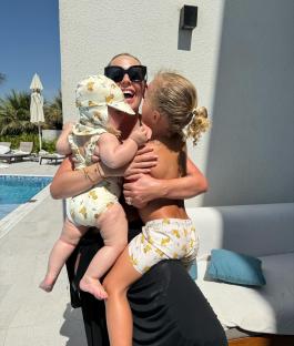 Woman hugging two young children by a pool.