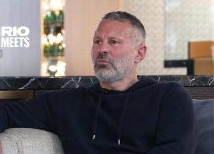 Man in dark hoodie sits on a couch and looks to the side.