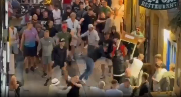 Large group of people fighting in a narrow street.