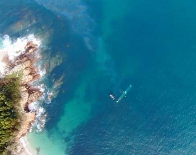 Aerial view of a submarine near a rocky coastline.