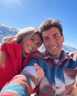 Selfie of a couple in winter clothing in front of a snowy mountain.