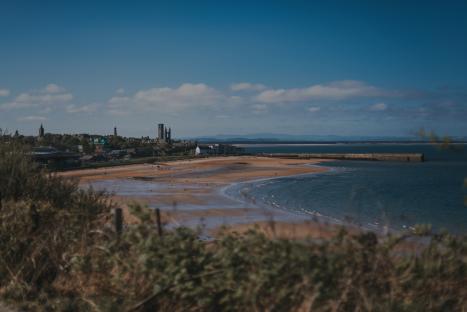 East Sands beach in St Andrews, Scotland, with St Andrews Cathedral and St Salvator's Chapel in the background.