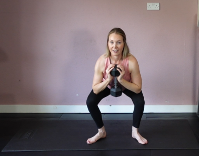 Woman performing a squat with a dumbbell.