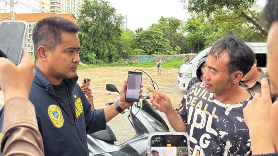 Police officer showing a suspect a phone.