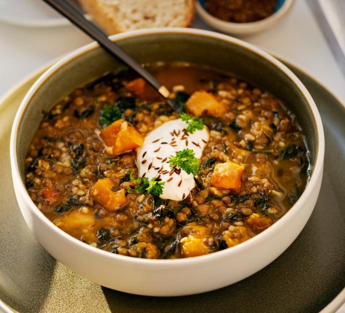 Bulgur wheat, lentil, butternut squash, and spinach soup garnished with a dollop of yogurt, parsley, and toasted cumin seeds.