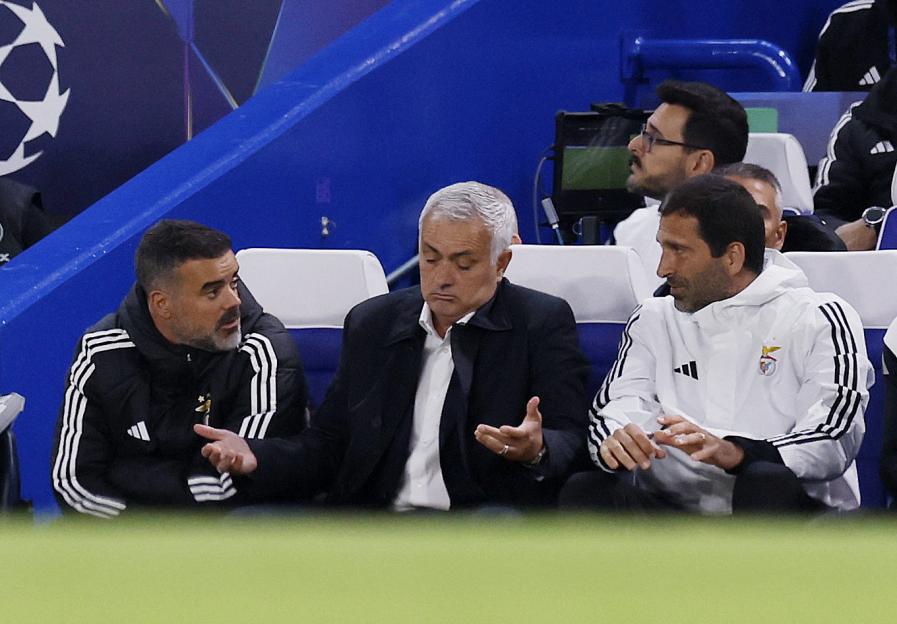 Benfica coach Jose Mourinho looks on with assistant coaches Joao Tralhao and Pedro Machado during a football match.