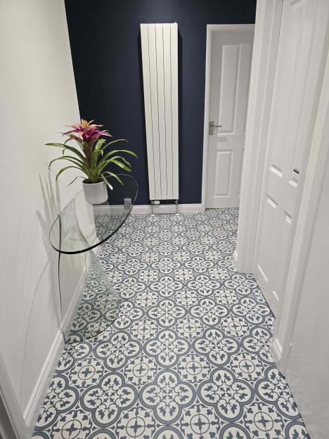 Hallway with patterned floor, glass console table, and plant.