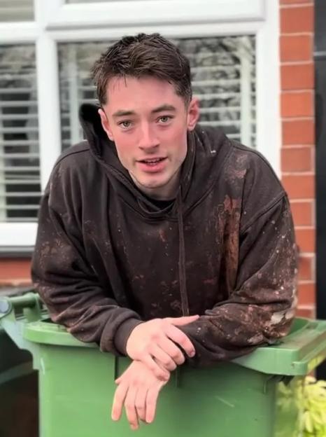 Man in dirty hoodie leaning on a green dumpster; text overlay: 