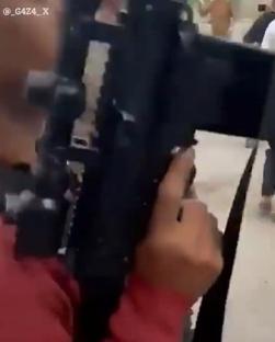 Person filming a street scene with a camera.