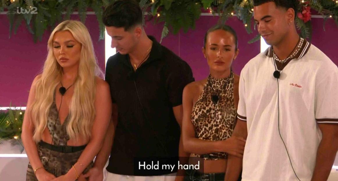 Islanders at the fire pit; one couple holds hands.