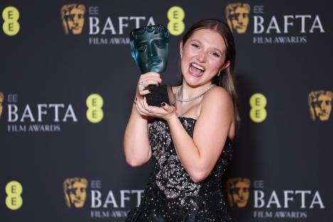 Mia McKenna-Bruce holding a BAFTA award.