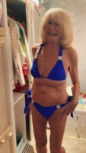 A smiling older woman in a blue bikini.