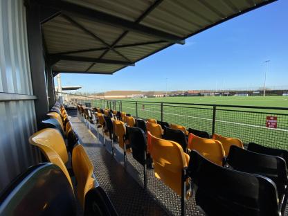 Empty covered stands overlooking a soccer field.