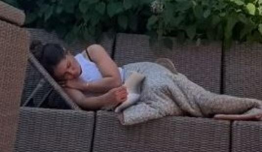 Woman relaxing on patio furniture while reading a book.