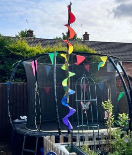 Trampoline decorated with rainbow flags and wind spinner.