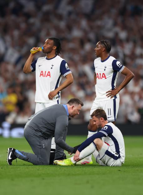 Injured James Maddison of Tottenham Hotspur receiving medical attention on the field.